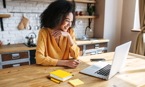 Woman in yellow shirt looking at laptop.