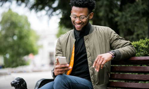 Un homme sur un banc sur son téléphone.