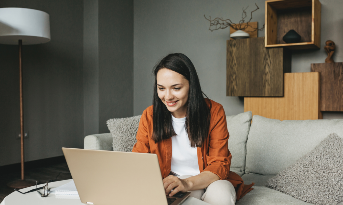 Woman looking at laptop on couch.