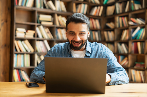 Un homme travaille joyeusement sur son ordinateur portable