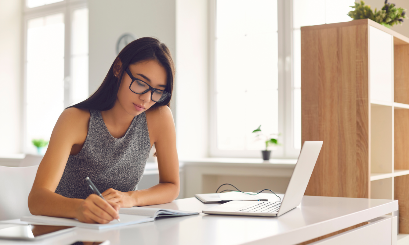 Frau beim Schreiben neben dem Laptop_Blog