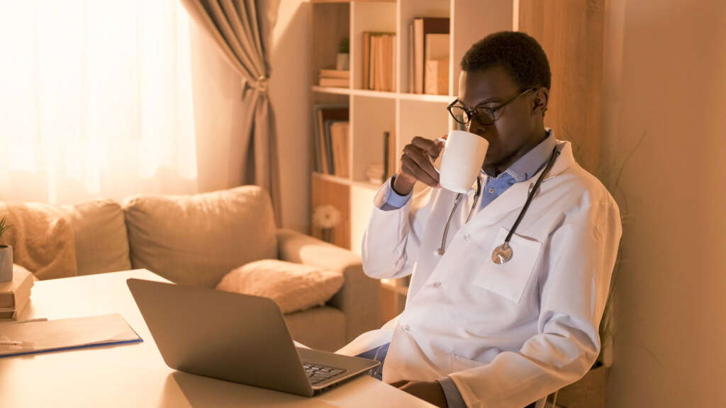 Relaxed doctor watches online continuous medical education while drinking tea