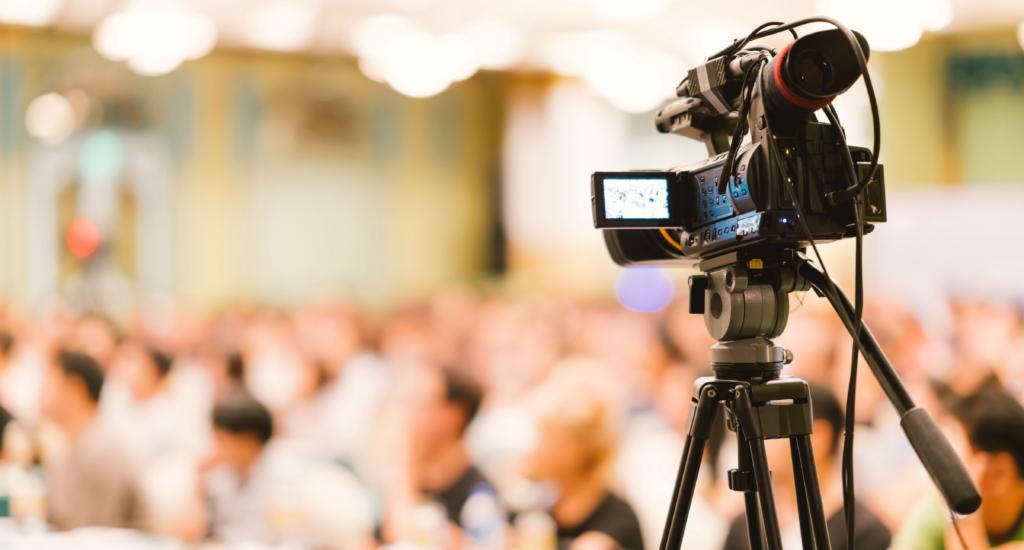A video camera facing a crowd.