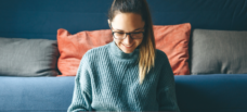 A person in a blue sweater looking at a laptop.