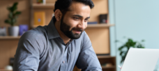 A smiling man working on a laptop.