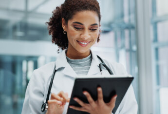 Doctor at hospital with tech. Using tablet to engage with digital content.