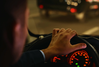 Man behind wheel of car at night.