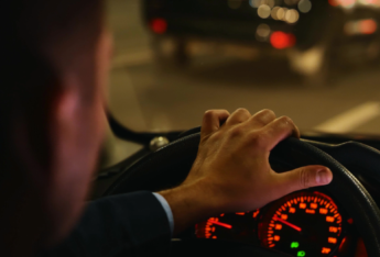 Man behind wheel of car at night time.